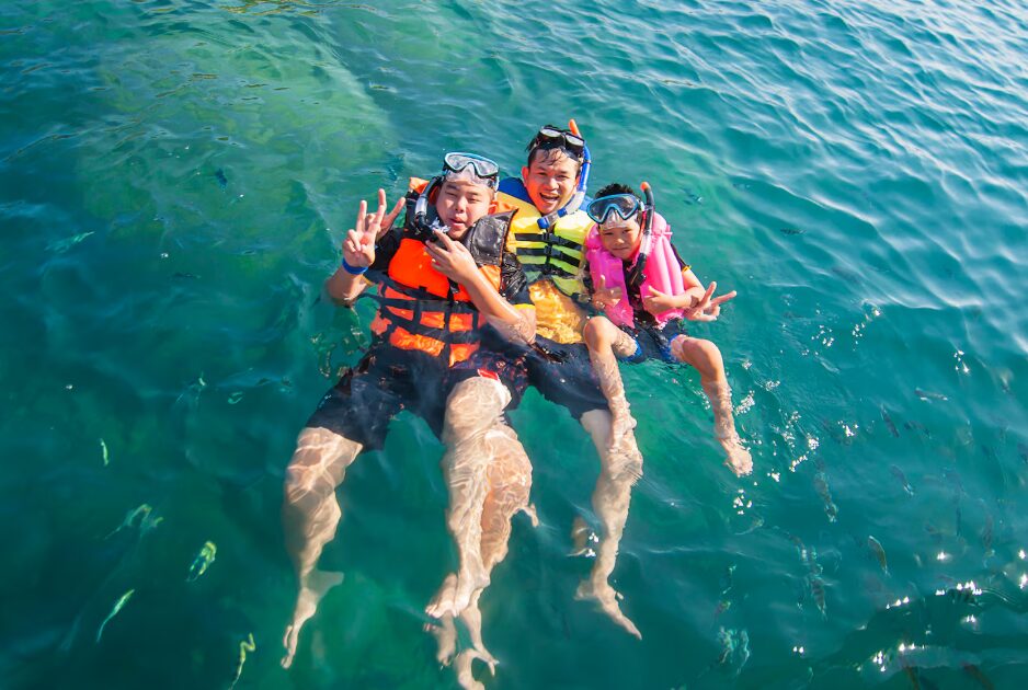 Travelers enjoying swimming and sunbathing on white sand under blue skies, highlighting the best time to visit Cam Ranh during the dry season.
